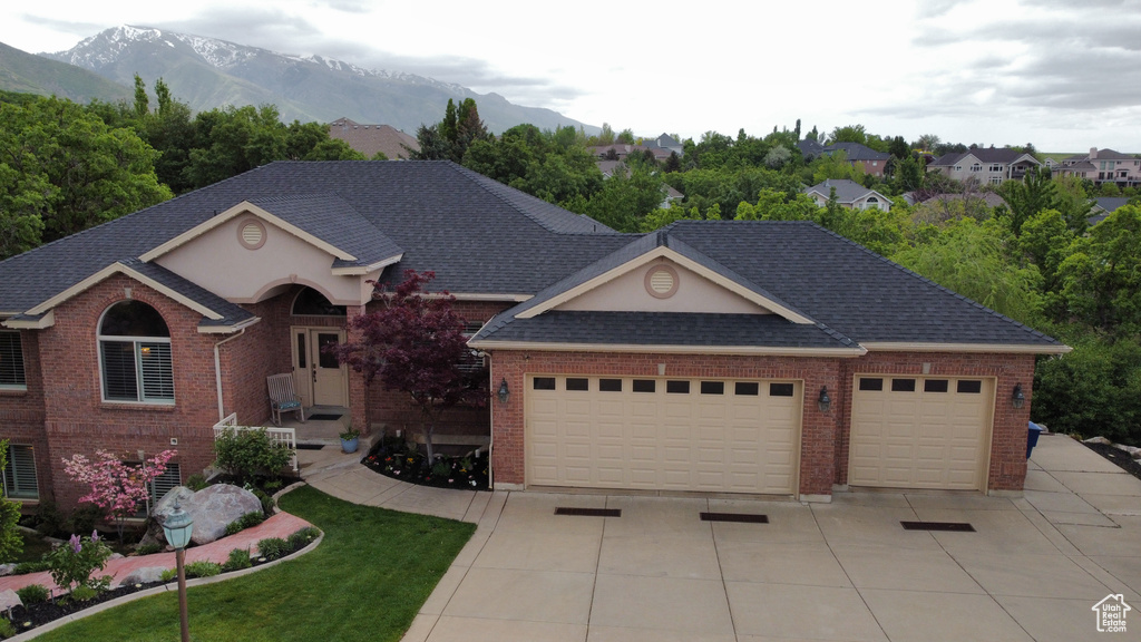 Ranch-style house featuring a garage, concrete driveway, a mountain view, and brick siding