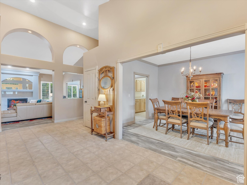 Dining area with a towering ceiling, recessed lighting, a warm lit fireplace, a chandelier, and baseboards