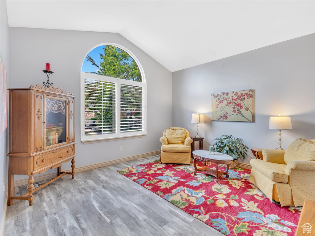 Living area with vaulted ceiling, wood finished floors, and baseboards