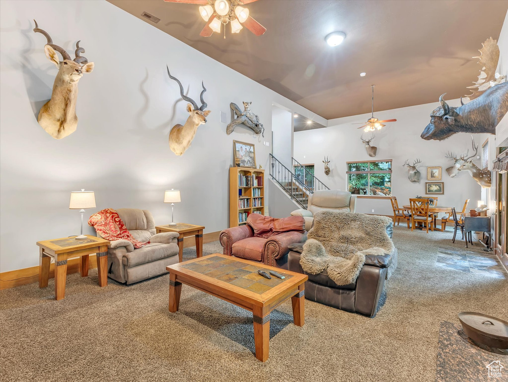 Living area with ceiling fan, carpet, stairway, and baseboards