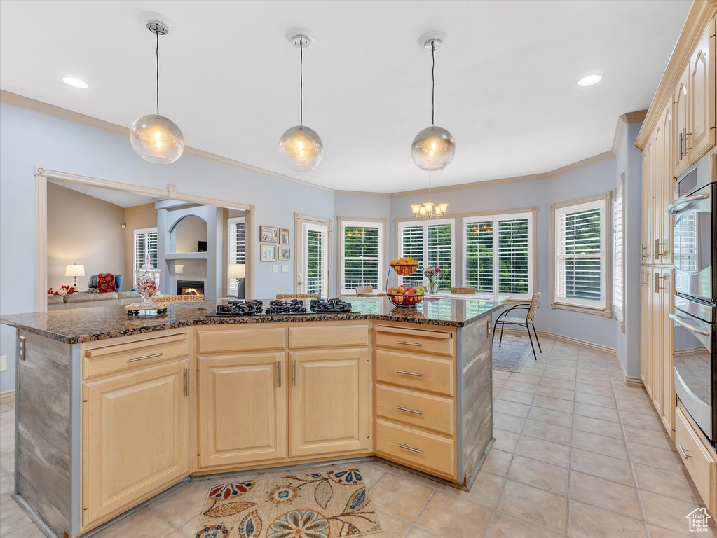 Kitchen featuring black gas stovetop, light brown cabinetry, crown molding, light tile patterned floors, and a lit fireplace