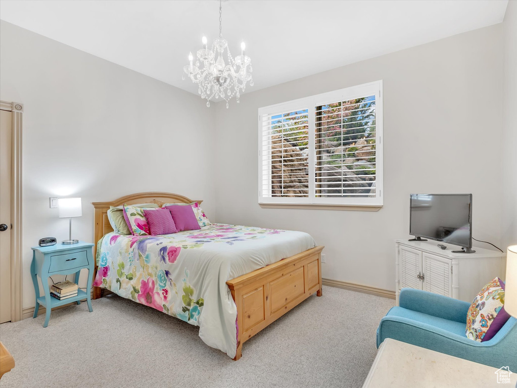 Carpeted bedroom with a chandelier and baseboards