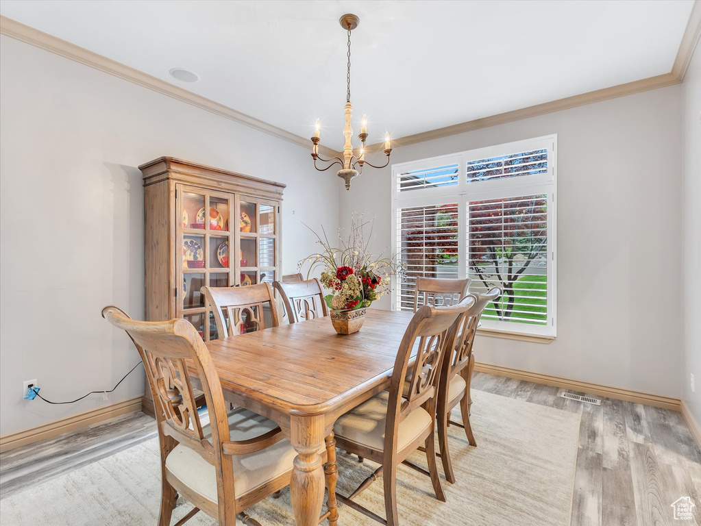 Dining space with a chandelier, crown molding, light wood-type flooring, and baseboards