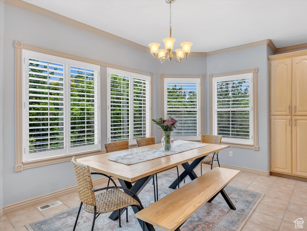 Dining area with a chandelier, light tile patterned floors, baseboards, and crown molding