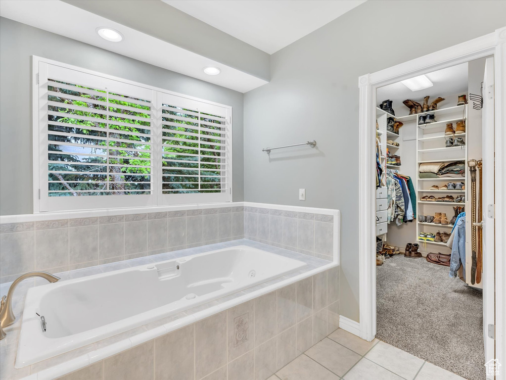 Full bath featuring tile patterned floors, a spacious closet, and a garden tub