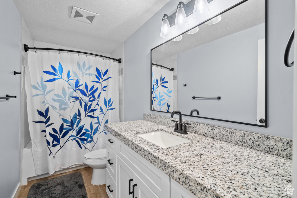 Bathroom featuring toilet, vanity, wood finished floors, and shower / bath combo