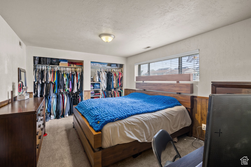 Bedroom featuring multiple closets, a textured ceiling, and carpet floors