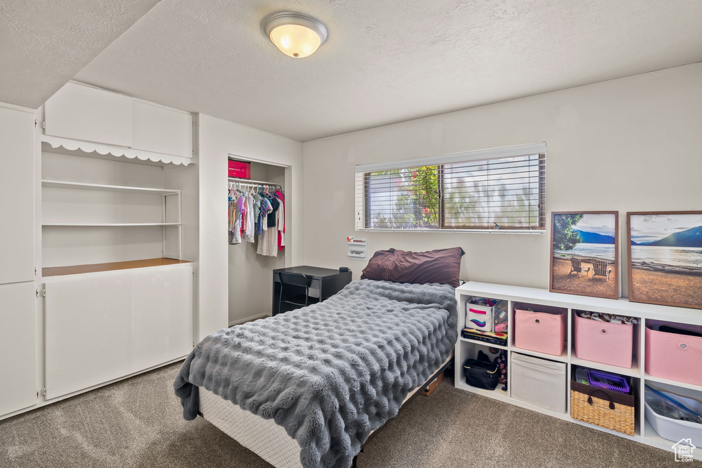 Carpeted bedroom featuring a textured ceiling and a closet