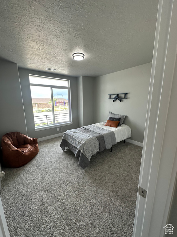 Carpeted bedroom featuring a textured ceiling and baseboards