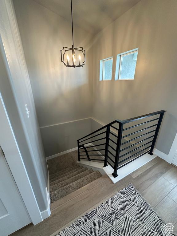 Stairs with a chandelier, wood finished floors, and baseboards