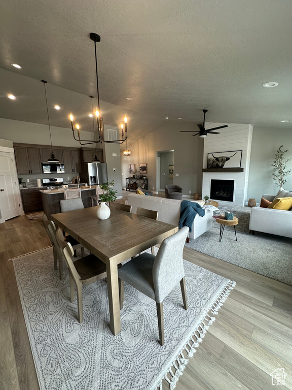 Dining room with wood finished floors, recessed lighting, a fireplace, a ceiling fan, and a chandelier