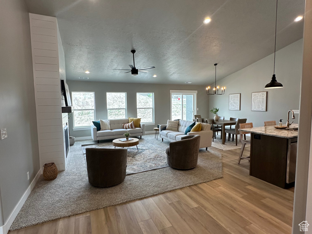Living room with wood finished floors, a chandelier, a ceiling fan, recessed lighting, and baseboards