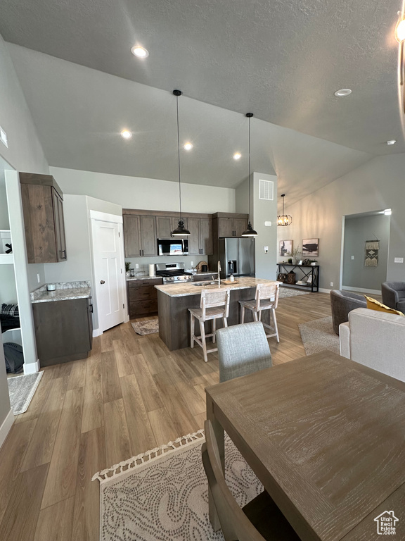 Dining area with lofted ceiling, light wood-type flooring, recessed lighting, and a textured ceiling