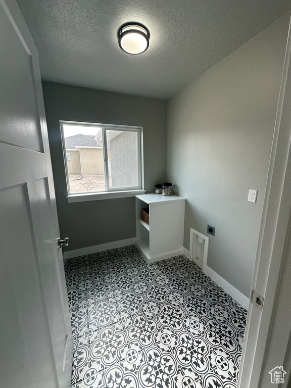 Washroom with hookup for an electric dryer, a textured ceiling, and baseboards