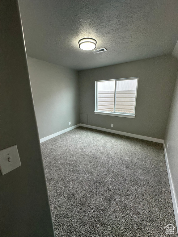 Unfurnished room with baseboards, a textured ceiling, and carpet floors