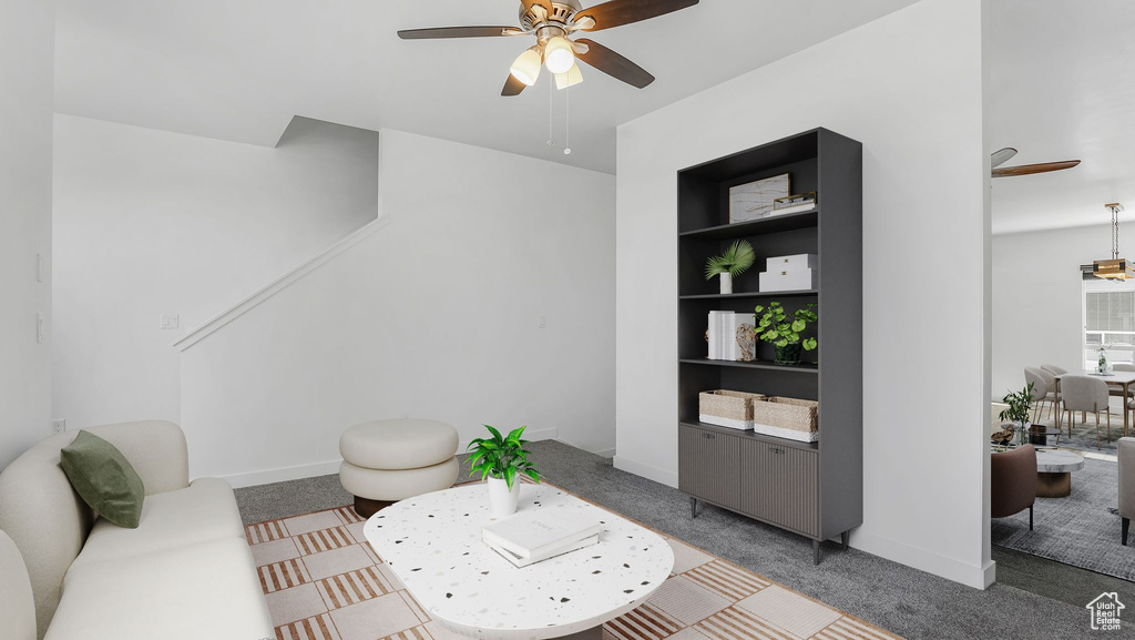 Carpeted living room with ceiling fan, built in shelves, and baseboards