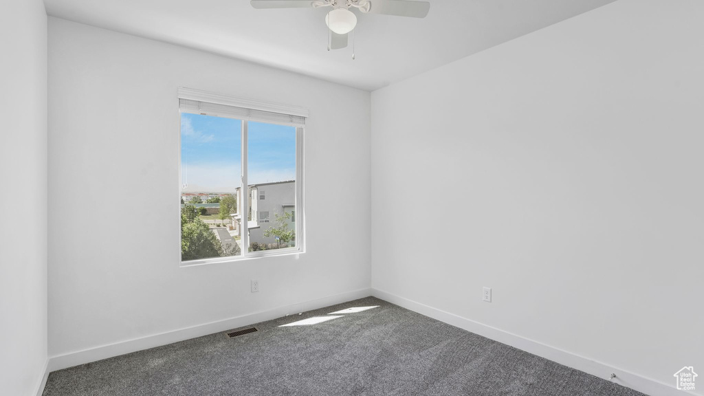 Carpeted empty room with a ceiling fan and baseboards