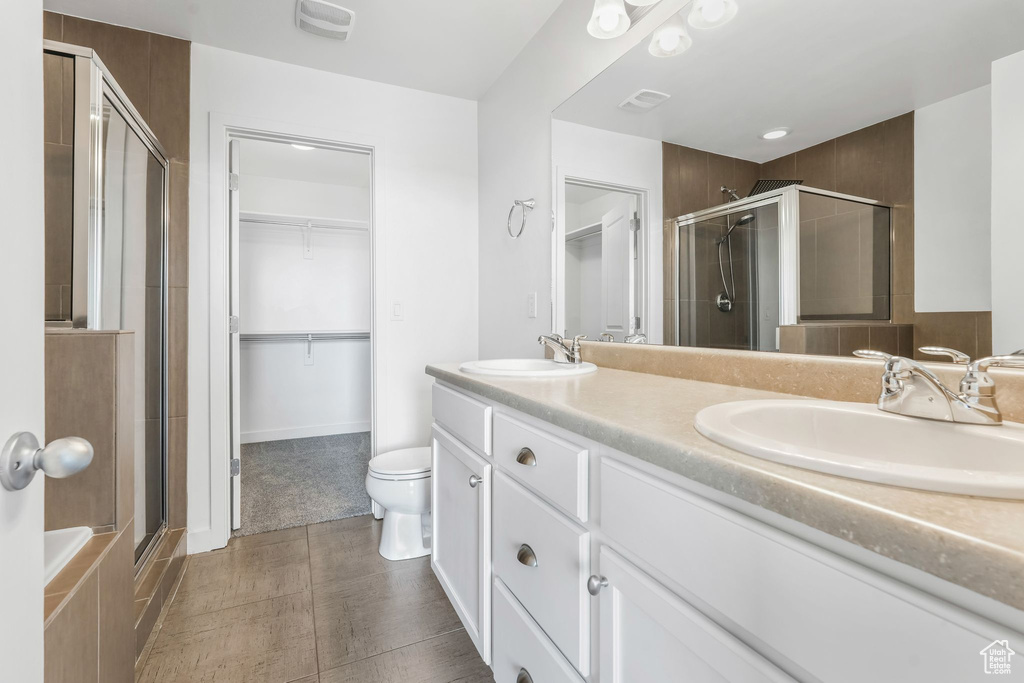 Bathroom with a stall shower, a spacious closet, double vanity, and tile patterned flooring