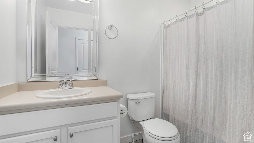 Full bath with toilet, vanity, and curtained shower