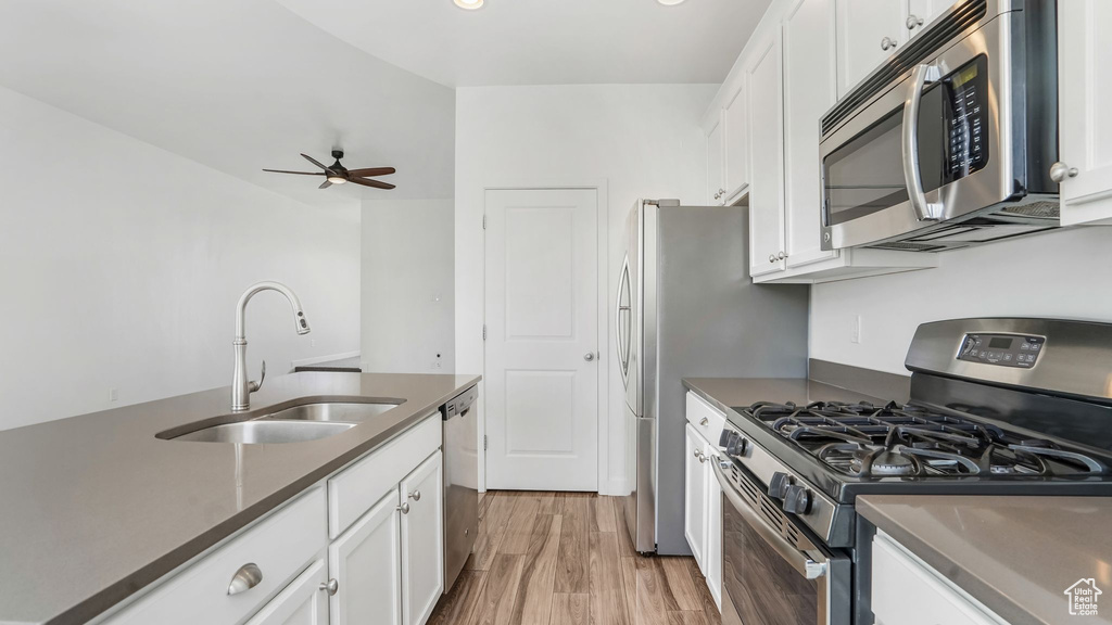 Kitchen with appliances with stainless steel finishes, a sink, dark countertops, white cabinetry, and recessed lighting
