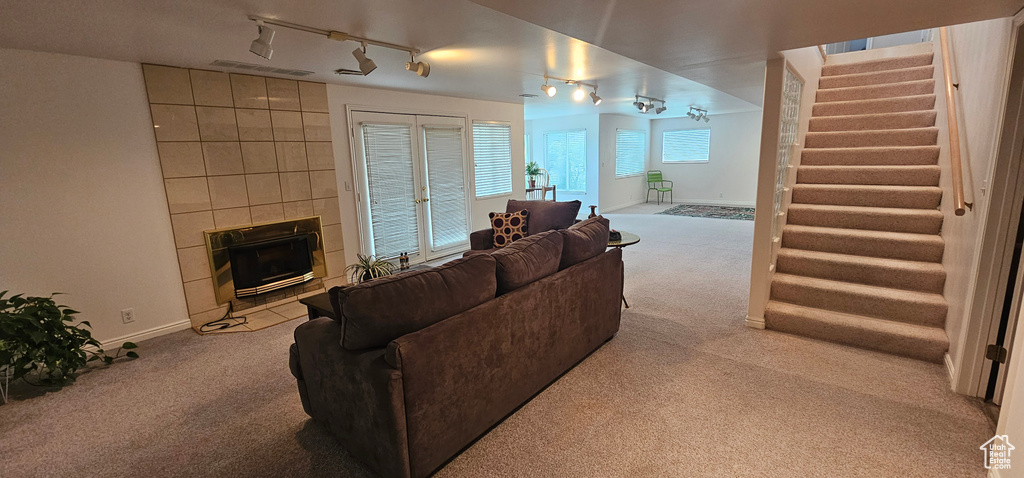 Living area with carpet flooring, track lighting, stairway, and a tile fireplace