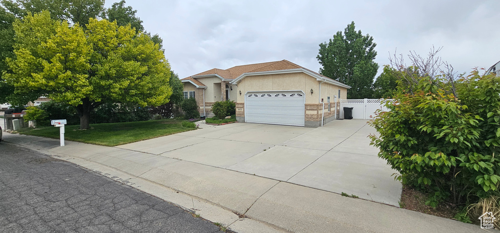 Single story home featuring stucco siding, driveway, and a garage