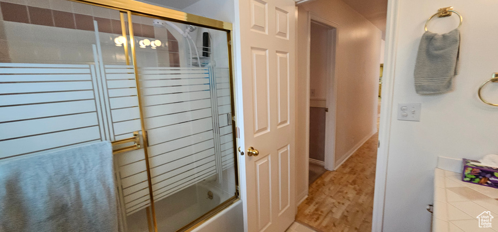 Full bathroom featuring wood finished floors and combined bath / shower with glass door