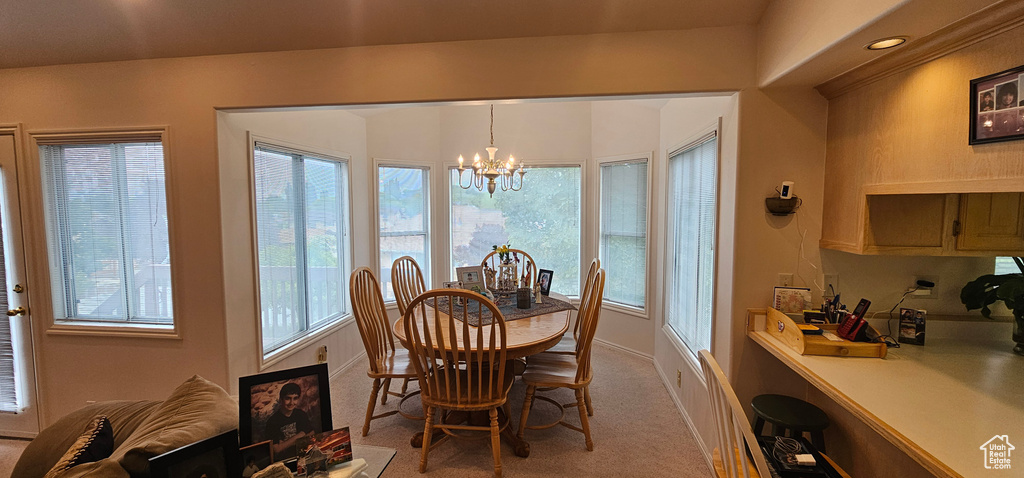 Carpeted dining space featuring a chandelier and baseboards