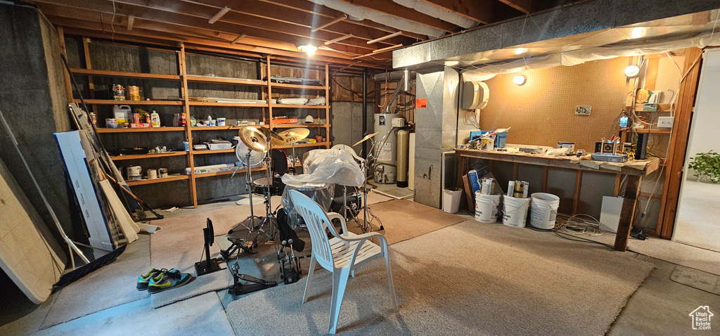 Unfinished basement with water heater, heating unit, and a workshop area