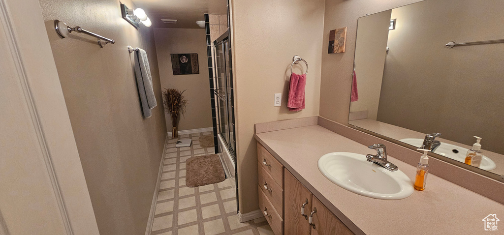 Full bath with tile patterned floors, vanity, and a shower
