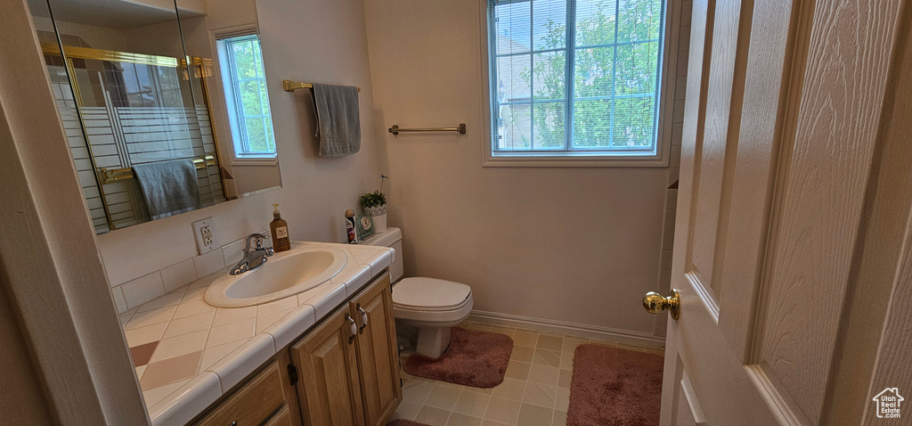 Full bathroom with toilet, vanity, an enclosed shower, and baseboards