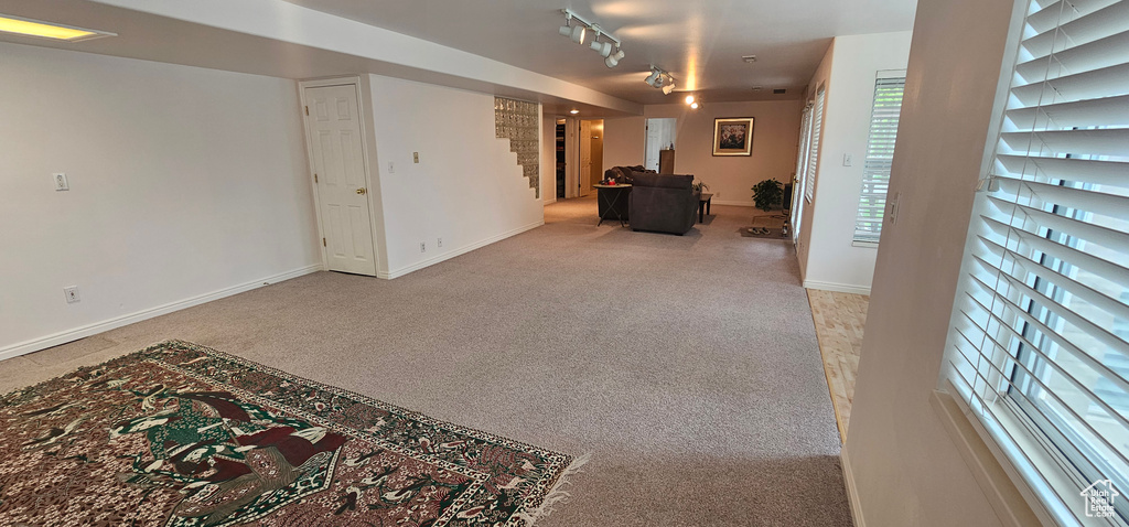 Living room featuring carpet flooring, stairs, baseboards, and rail lighting