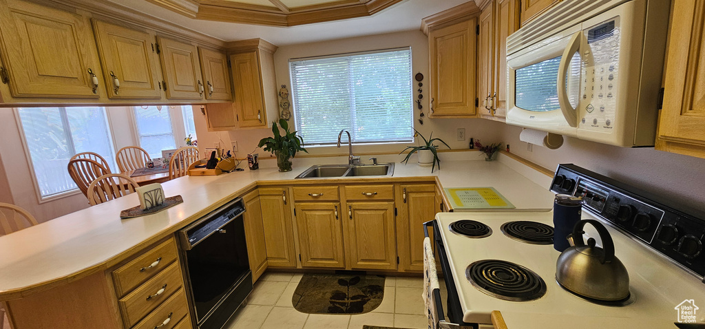 Kitchen featuring white microwave, electric range, a sink, black dishwasher, and a peninsula