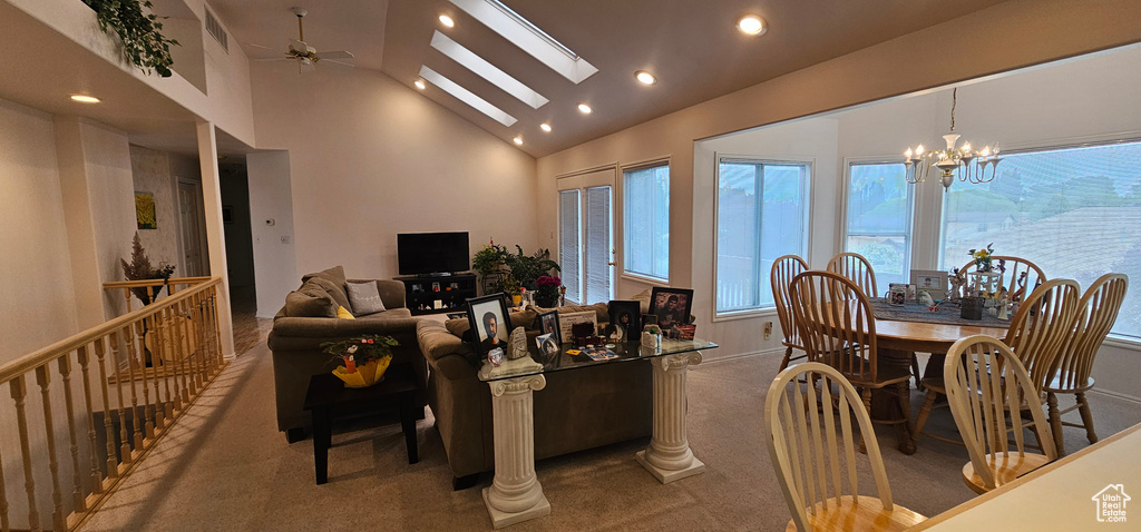 Carpeted living area with vaulted ceiling, plenty of natural light, recessed lighting, a ceiling fan, and a chandelier