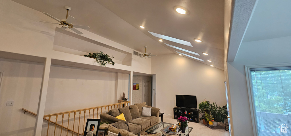 Living room featuring ceiling fan, carpet, vaulted ceiling, a skylight, and recessed lighting