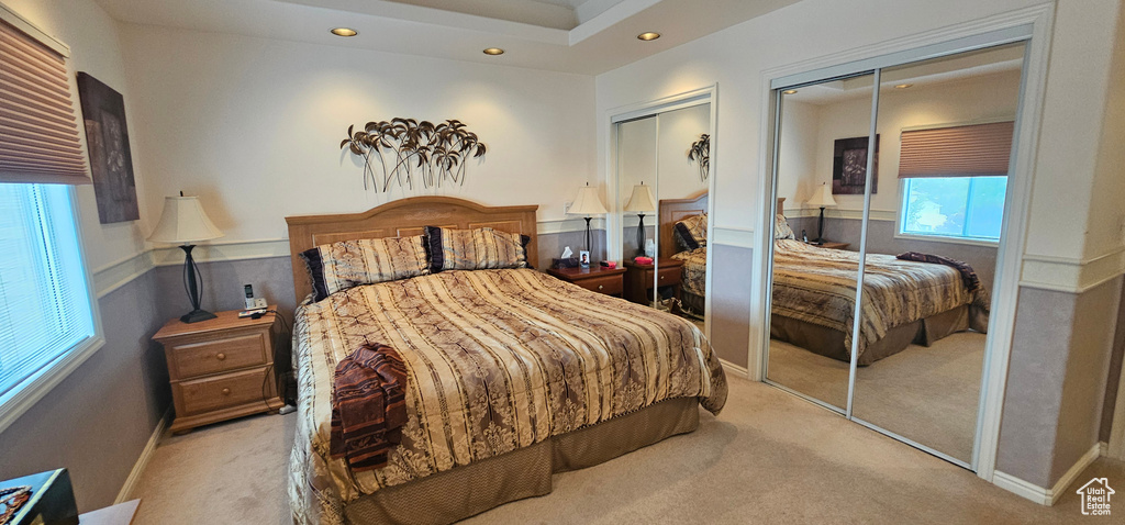 Bedroom featuring two closets, light colored carpet, and recessed lighting