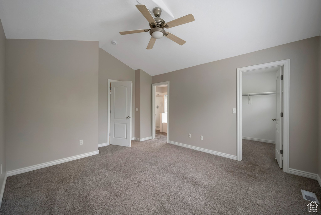Unfurnished bedroom with carpet flooring, baseboards, a spacious closet, and lofted ceiling