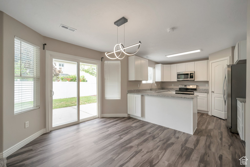 Kitchen featuring stainless steel appliances, wood finished floors, a sink, and baseboards