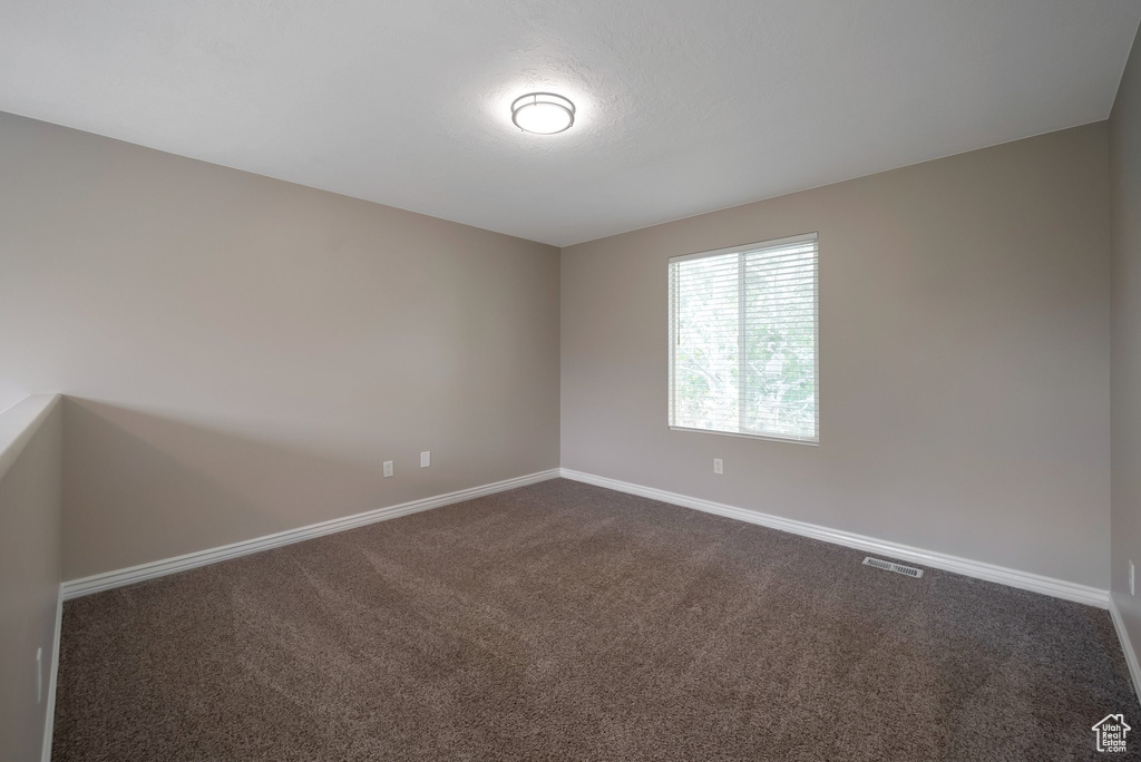 Empty room with dark carpet and baseboards