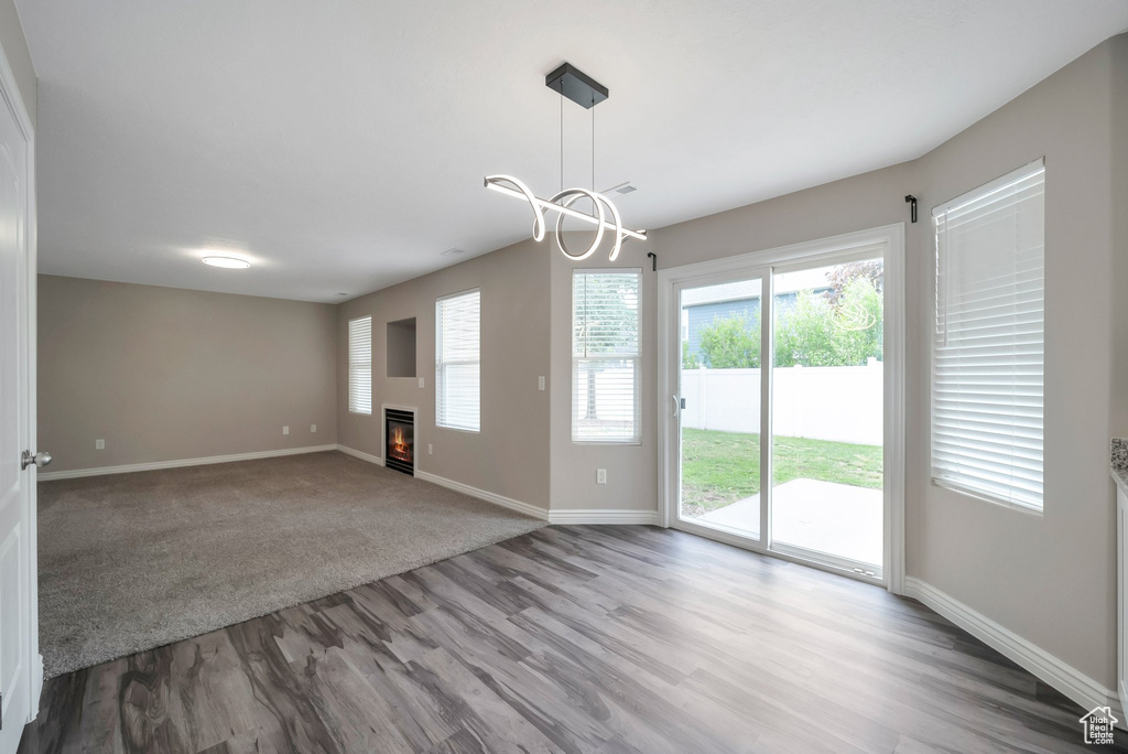 Spare room with wood finished floors, baseboards, a glass covered fireplace, and a chandelier