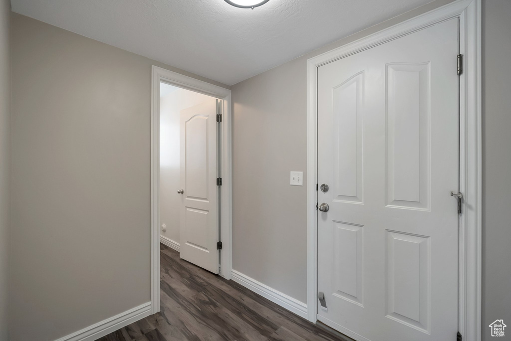 Hall with dark wood-style flooring and baseboards