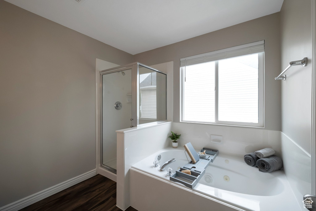 Full bathroom featuring a shower stall, a whirlpool tub, wood finished floors, and baseboards