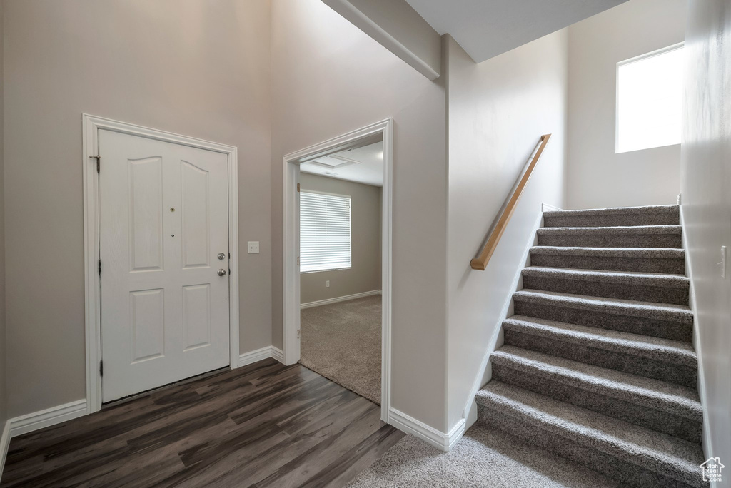 Foyer entrance featuring dark wood-style floors, stairs, and baseboards