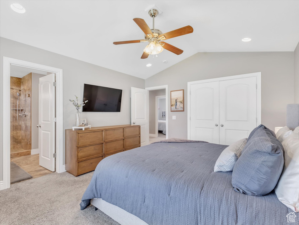 Bedroom with vaulted ceiling, light carpet, a closet, a ceiling fan, and ensuite bath