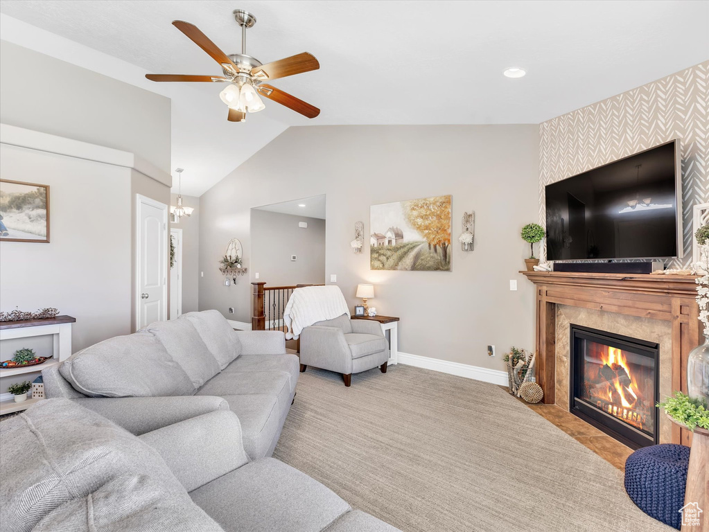 Living room featuring baseboards, vaulted ceiling, a ceiling fan, a high end fireplace, and carpet floors