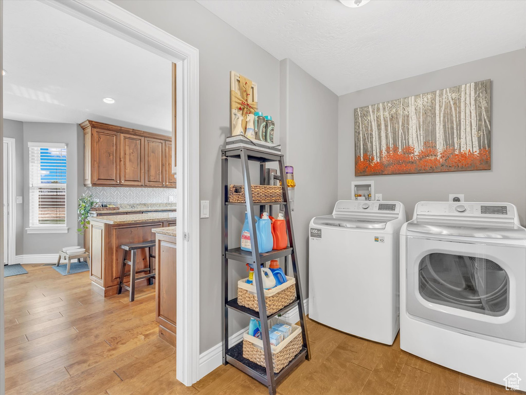 Clothes washing area featuring washer and dryer, light wood-style flooring, baseboards, and recessed lighting