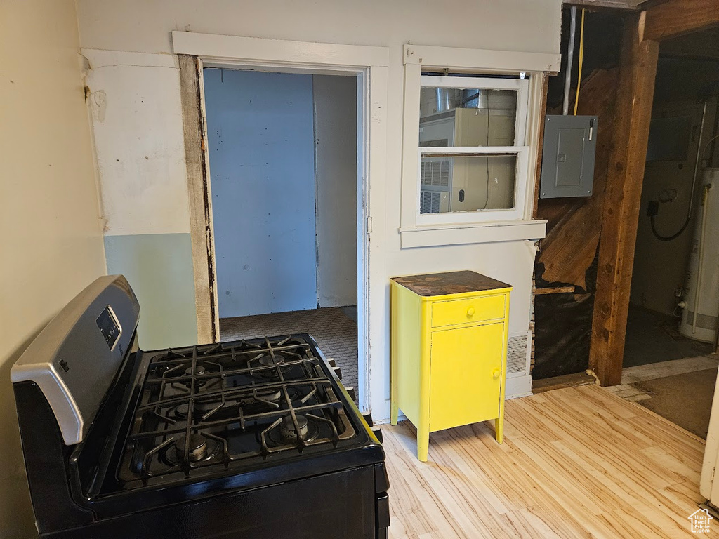 Kitchen with stainless steel range with gas cooktop, electric panel, wood finished floors, and gas water heater