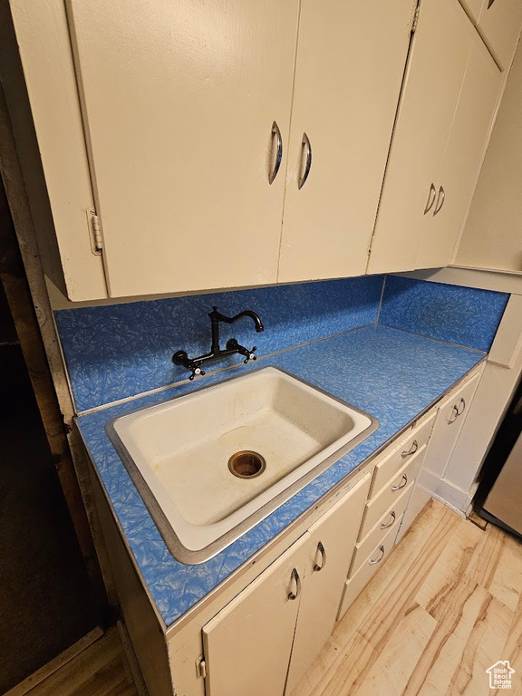 Kitchen with a sink, light wood-type flooring, and white cabinets