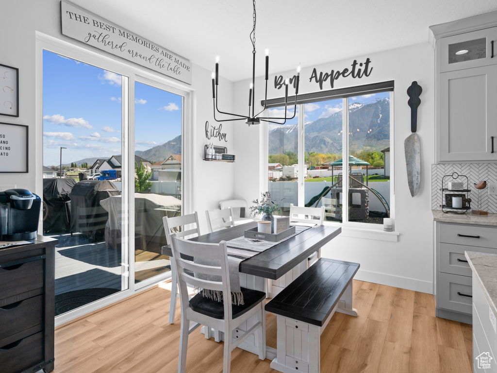 Dining space with a chandelier, a mountain view, light wood finished floors, and baseboards