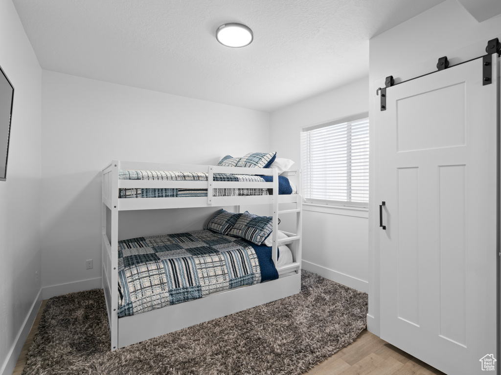 Bedroom featuring a barn door, baseboards, and wood finished floors